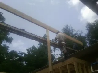 Carpenter setting a ridge beam over a new addition frame — Ice Dam Removal by Roofing Brothers in Fort Eustis