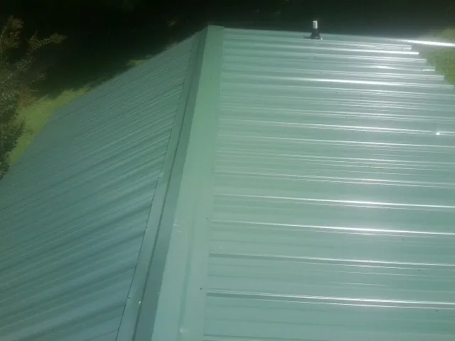 New green metal panels meeting at the ridge of a roof — Flat Roof Repair work by our crew in Fort Eustis