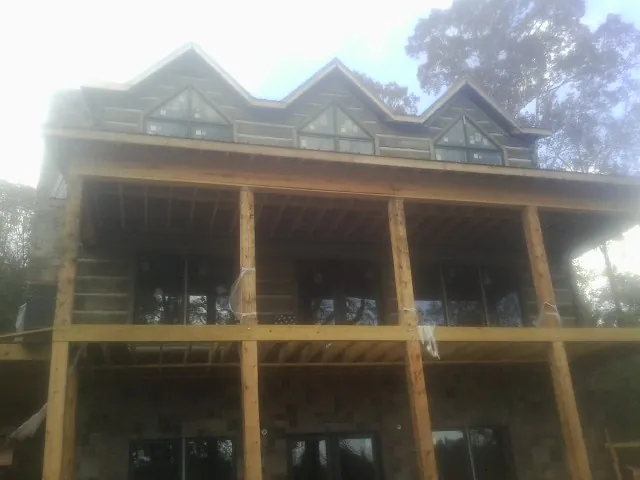 Dormers and porch framing on a large log home under construction — Roof Coating work by our crew in Fort Eustis