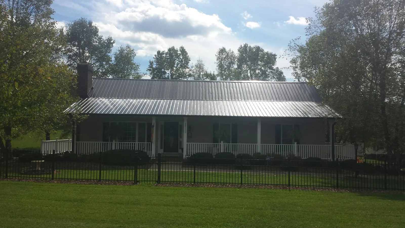 Gray metal roof on a brick ranch with a full width front porch — Gutter Guard Installation work by our crew in Fort Eustis