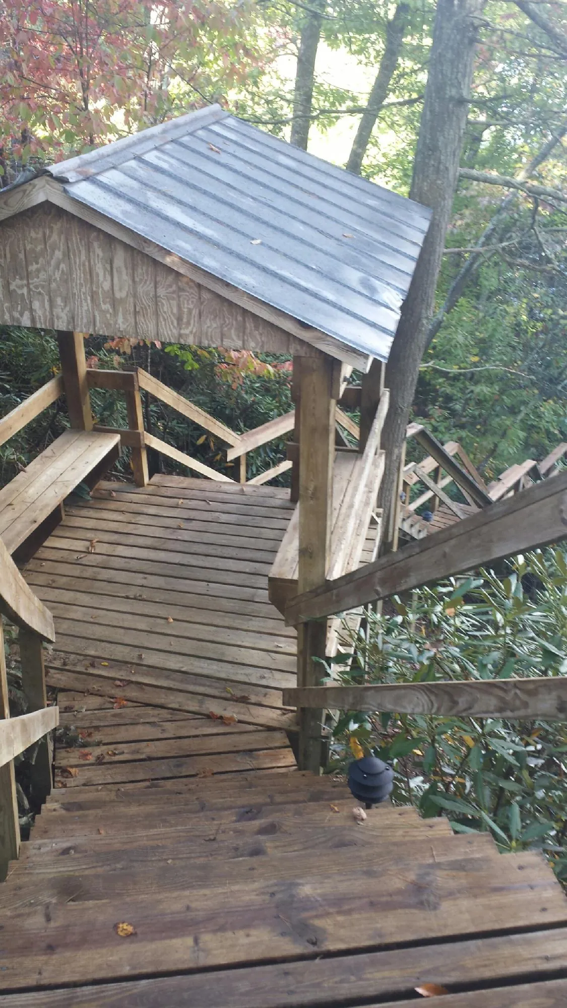 Metal roofed shelter over wooden steps on a wooded walkway — Skylight Repair & Installation work by our crew in Fort Eustis